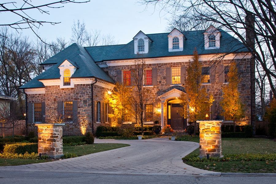 Brick residence photographed in the evening with a broad circular drive and lit entry.