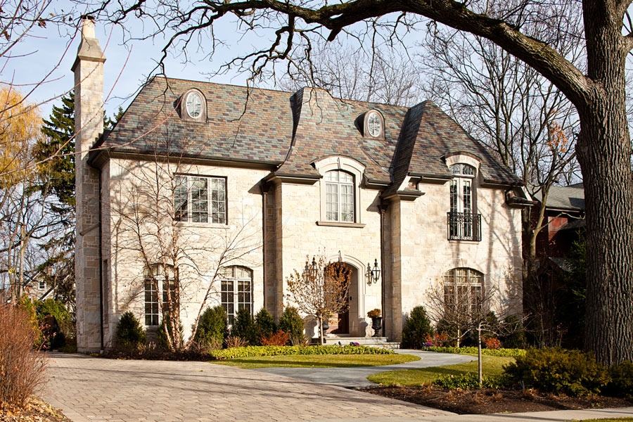 Light masonry residence with arched upper windows and a compact urban front garden.