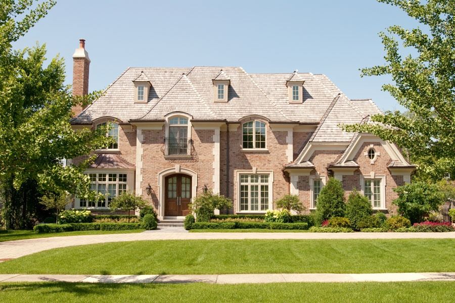 Brick residence with a slate roof, broad lawn and symmetrical front composition.