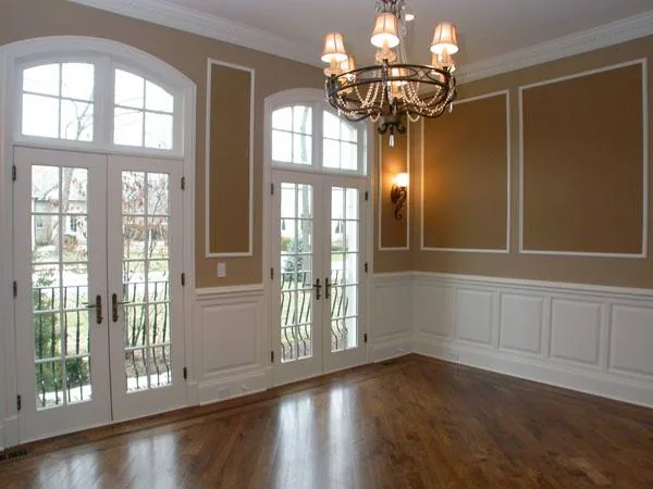 Unfurnished dining room with paneling, arched windows and timber flooring.
