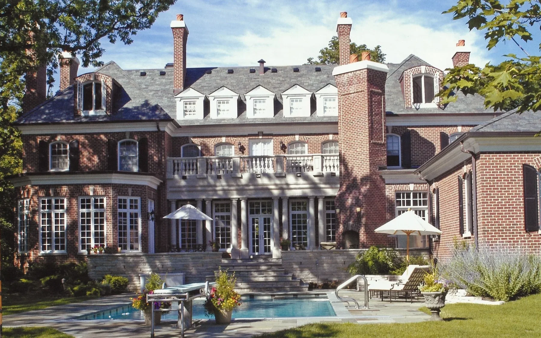 Rear elevation of a red-brick SGE residence with terrace and swimming pool.