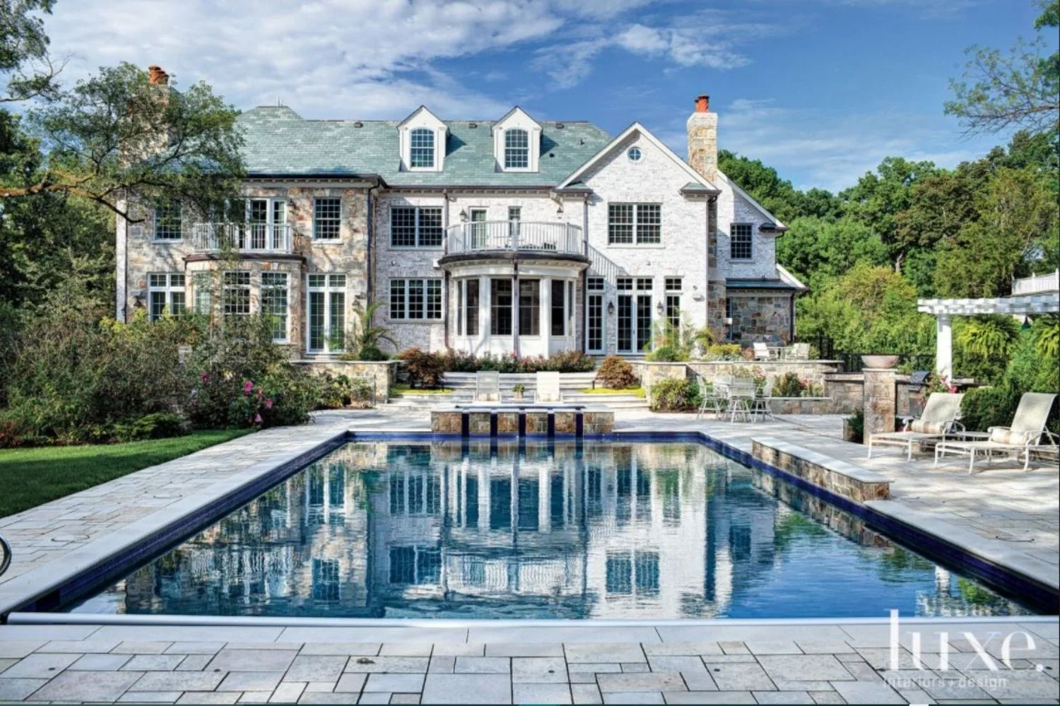 Rear elevation of an SGE residence beyond a long rectangular swimming pool and terrace.