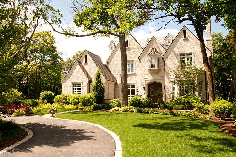 Light-colored SGE residence approached through mature trees and landscape.