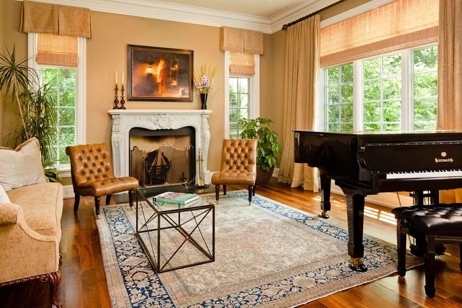 Living room with a fireplace, grand piano and garden-facing windows.