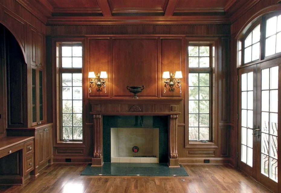 Paneled library with a coffered timber ceiling and a fireplace between tall windows.